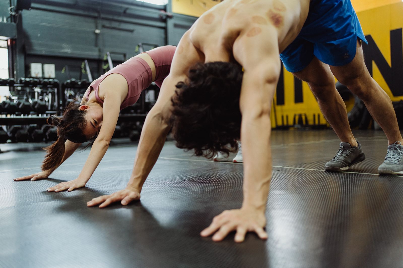 Two people moving through a controlled mobility drill in a gym